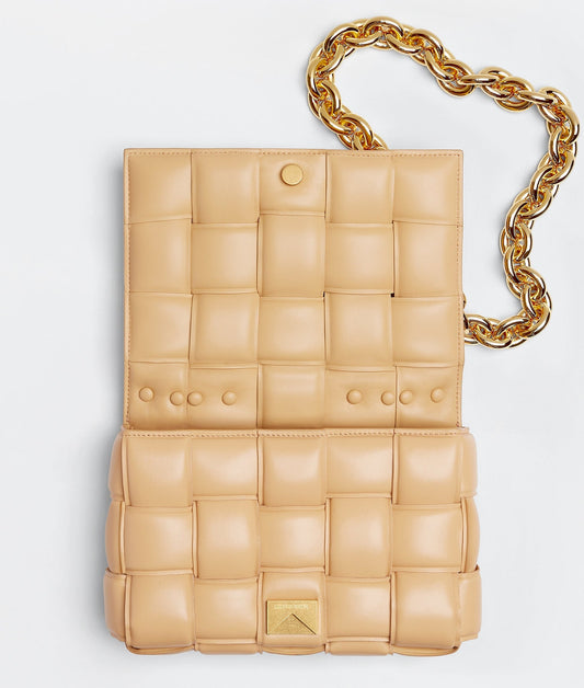 Beige quilted handbag with a gold chain on a light gray background