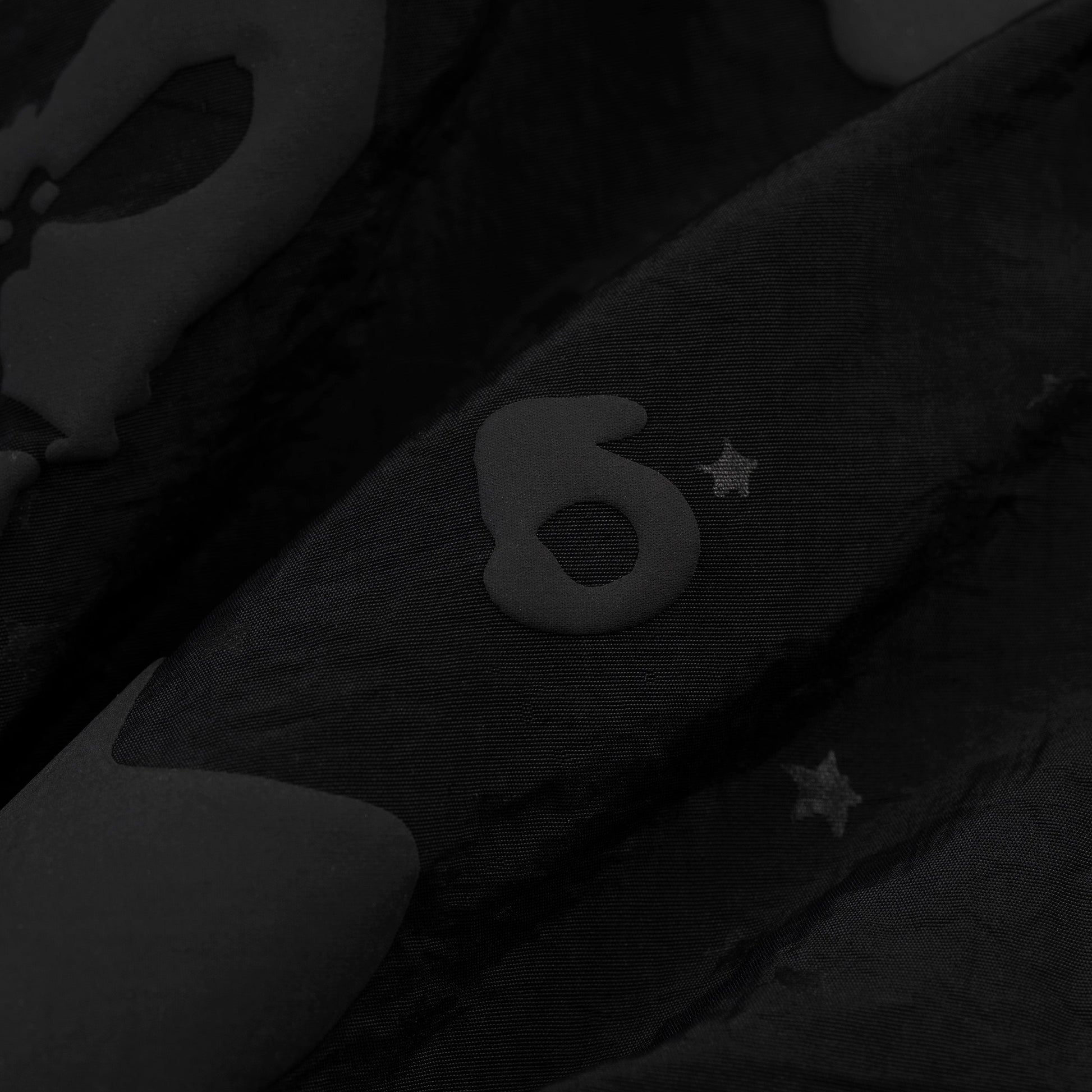 Detail view of Beluga puff print on SP5DER short in Black