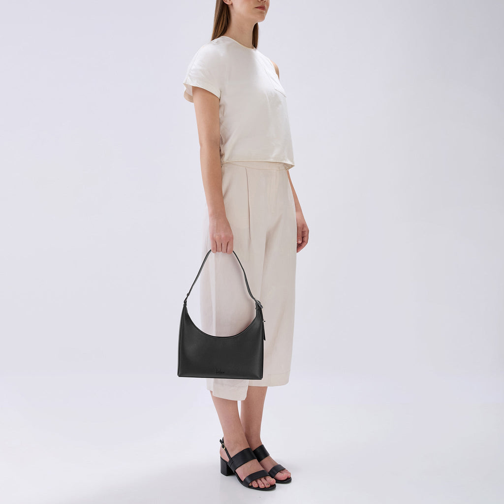 Bag It Danny Flatiron black leather shoulder bag carried by hand