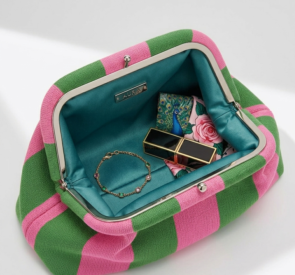 Open green and pink striped handbag with jewelry and makeup items on a white background