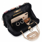 Black handbag with jewelry and phone on a white background