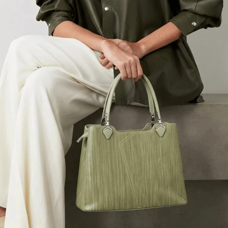 Person holding a green handbag with a neutral background