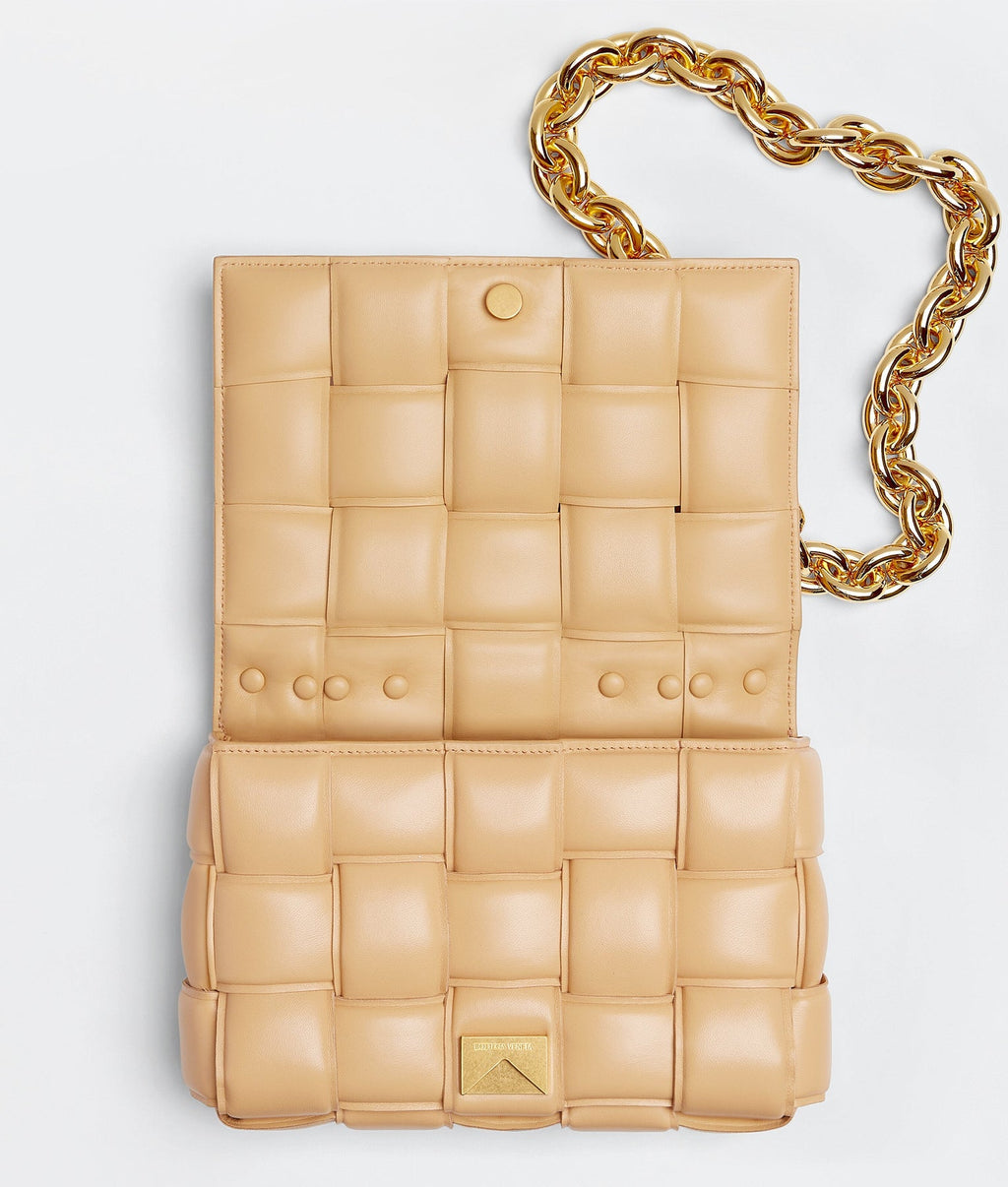 Beige quilted handbag with a gold chain on a light gray background