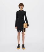 Person wearing a black outfit with a gold handbag on a white background
