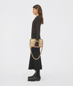 Woman holding a beige handbag with gold chain strap on a white background