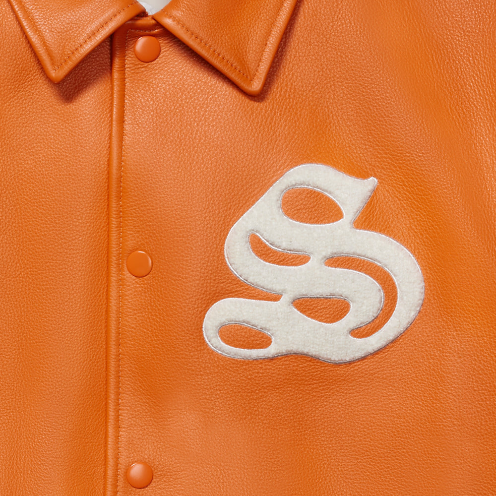 Detail view of embroidered 'S' patch on SP5DER Orange Leather Varsity Jacket