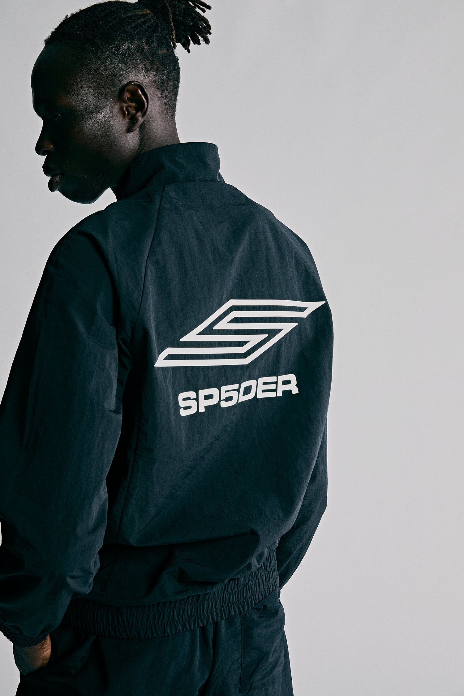 Model wearing SP5DER Pro Windbreaker in Black side view